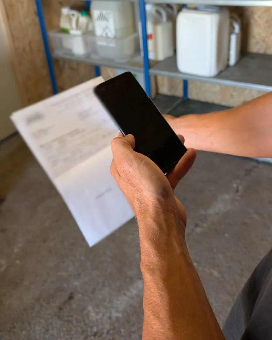 Un agriculteur photographie un bon de livraison avec son téléphone
